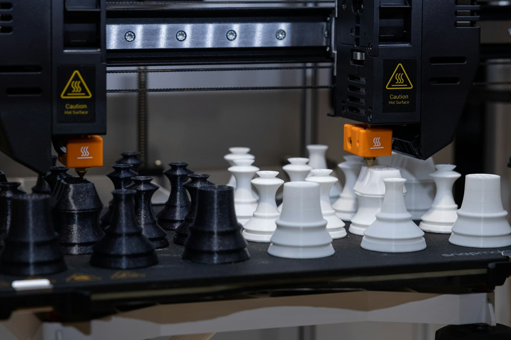 Batch of identical 3D printed parts on the beds of two printers