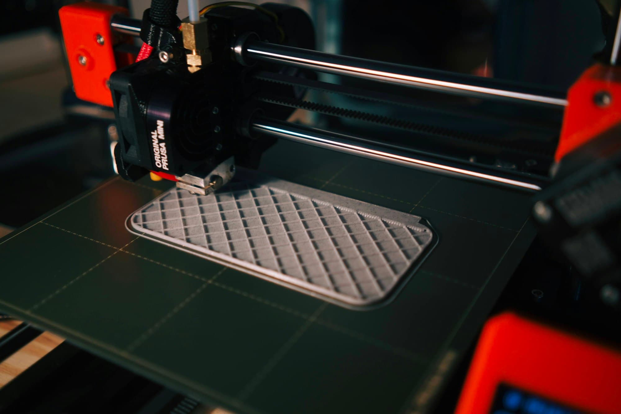 FDM 3D printer printing a grey textured part on its build plate